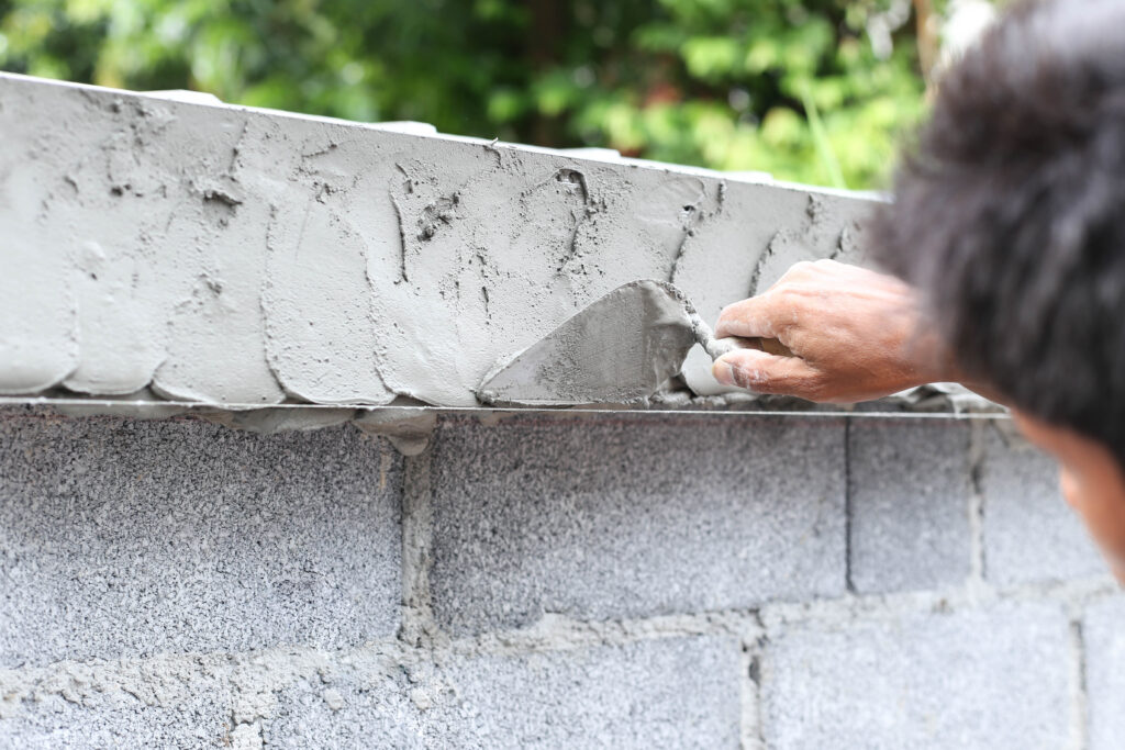 Man Troweling Cement onto a Concrete Block Wall